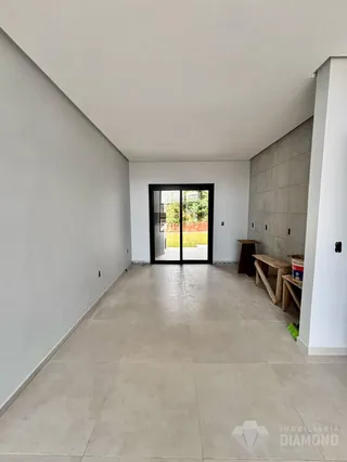 A sala apresenta paredes brancas e piso de concreto claro.