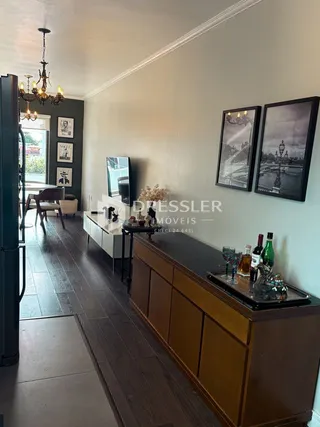 Vista de um corredor interno com piso de madeira e um móvel de madeira no primeiro plano.