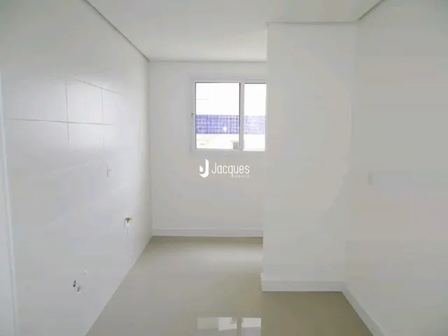 Foto interna de um ambiente claro com parede branca e janela.