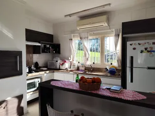 Vista da cozinha com armários brancos e bancadas escuras.