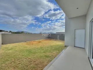 Vista externa de um terreno gramado ao lado de uma residência moderna.
