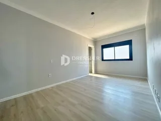 Uma sala de estar com piso de madeira clara e janela.