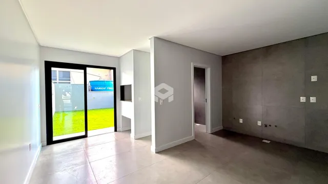 Uma vista interna de uma sala com porta de vidro que dá para o quintal.