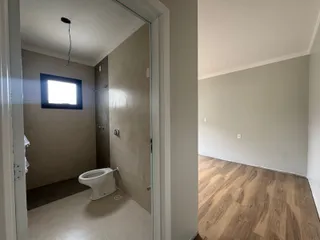 Banheiro com vaso sanitário branco e piso claro.