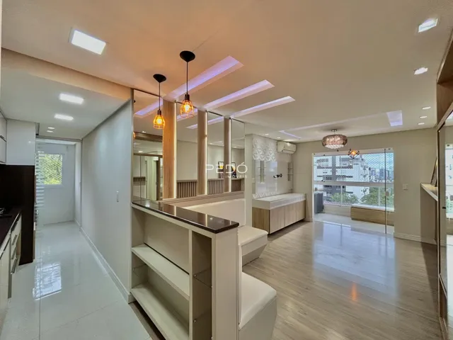 Ambiente interno de uma sala de estar moderna com piso de madeira clara e iluminação embutida.