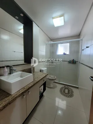 Foto de um banheiro com revestimento cerâmico e box de vidro.