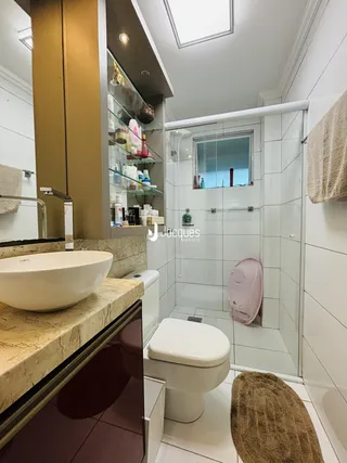 Banheiro moderno com box de vidro e louças brancas.