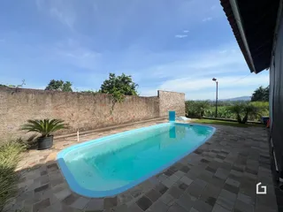Foto de uma piscina externa com muro de tijolos no fundo.