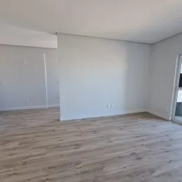Ambiente interno com paredes brancas e piso de madeira clara.
