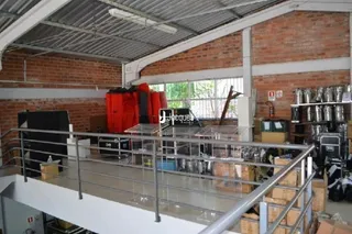 Vista interna de um espaço industrial com paredes de tijolo aparente e estrutura metálica.