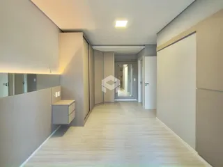 Hall de corredor com piso de madeira clara e armários embutidos.