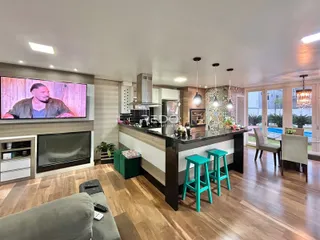 Sala de estar com cozinha integrada e piso de madeira em um imóvel no Brasil.