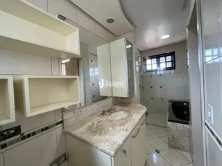 Banheiro com bancada de mármore e revestimento branco.