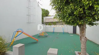 Uma área externa com grama sintética e equipamentos de playground.