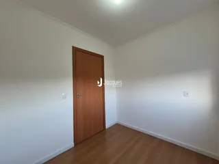 Vista interna de um ambiente com piso de madeira e porta de madeira.