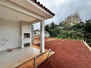 Vista da fachada de uma casa com área externa de terra no quintal.