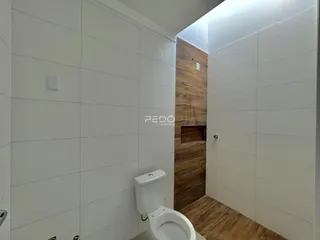 Interior de um banheiro com paredes brancas e detalhes em madeira.
