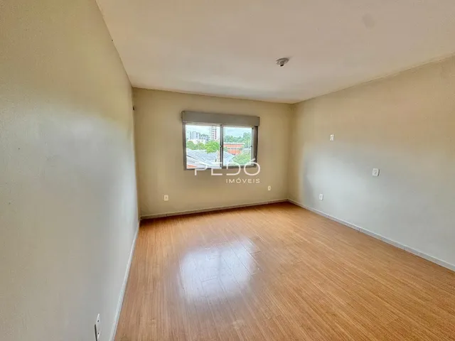 Uma sala com piso de madeira clara e janela.