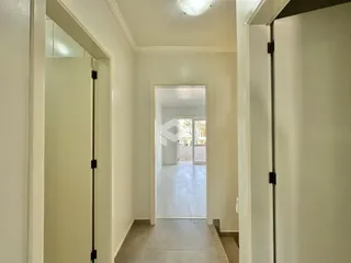 Hall de entrada com paredes brancas e piso claro.