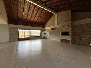 Ambiente interno amplo com piso de cerâmica e teto de madeira exposta.