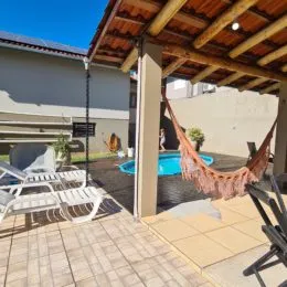 Área externa pavimentada com móveis de jardim e estrutura de cobertura.