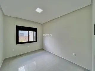 Interior de uma sala com paredes brancas e piso claro.