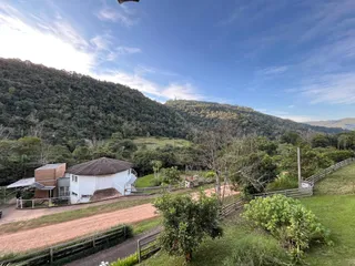 Vista externa de uma residência em Lajeado, Brasil, com paisagem montanhosa e vegetação exuberante ao fundo.