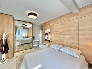 Quarto com paredes de madeira clara e cama de casal.