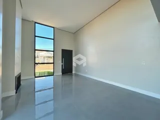 Interior de uma sala ampla com piso de concreto polido e grande janela.