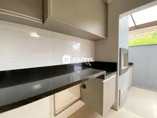 Esta é uma foto de uma cozinha moderna com bancada escura e armários brancos.