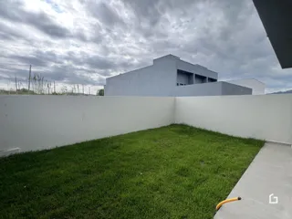 Vista externa de uma residência branca com jardim verde.