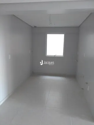 Vista interna de um corredor branco com uma janela.