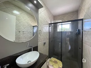 Uma foto de um banheiro com revestimento de cerâmica e box de vidro.