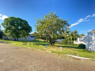 Vista externa de uma propriedade com área verde e árvores sob um céu azul.