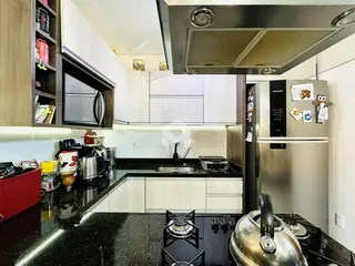 A cozinha moderna apresenta armários brancos e bancadas escuras.