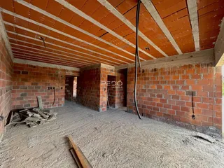 A foto mostra o interior de uma estrutura em construção com paredes de tijolo aparente.