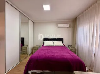 Quarto com cama grande e cortinas brancas.