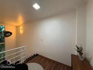Hall de entrada com piso de madeira e corrimão branco.