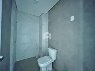 Vista de um corredor com um vaso sanitário em uma residência.