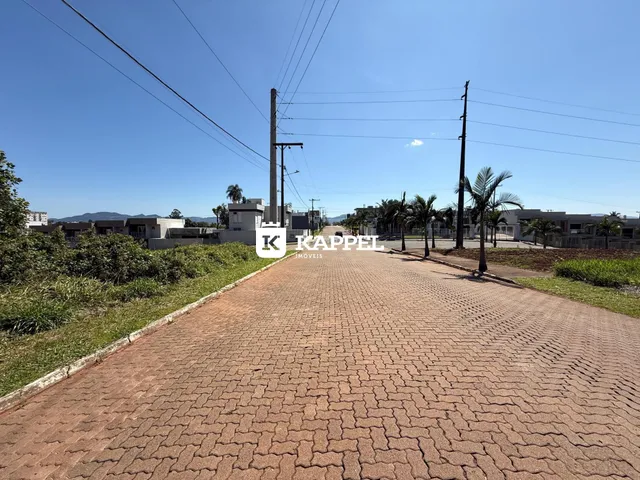 Vista externa de um caminho de tijolos vermelhos que leva a uma propriedade sob um céu claro.