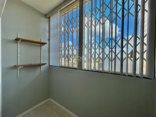 Vista de uma parede interna com janela decorativa e prateleira de madeira.
