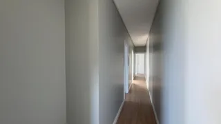 Corredor interno com paredes cinzas e piso de madeira.