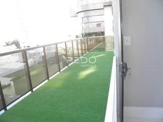 Vista de um ambiente com piso verde e grade de vidro.