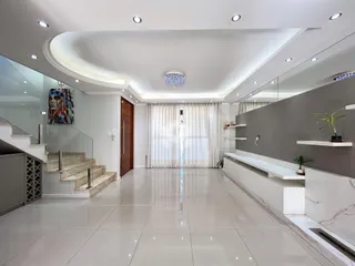 Uma área comum moderna com piso de mármore claro e escadaria de vidro.