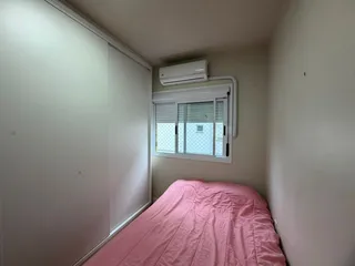 Quarto com cama e janela com ar condicionado instalado.