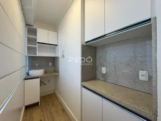 Interior de um corredor com armários brancos e piso de madeira clara.