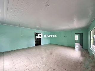Foto de um ambiente interno amplo com paredes verde-água e piso de cerâmica.