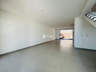 Corredor longo com piso claro e paredes brancas em um imóvel.