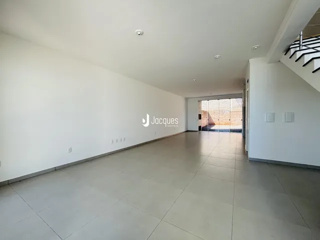 Corredor longo com piso claro e paredes brancas em um imóvel.
