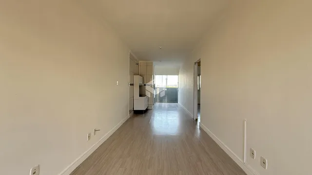 Corredor interno de uma residência com piso de madeira clara.